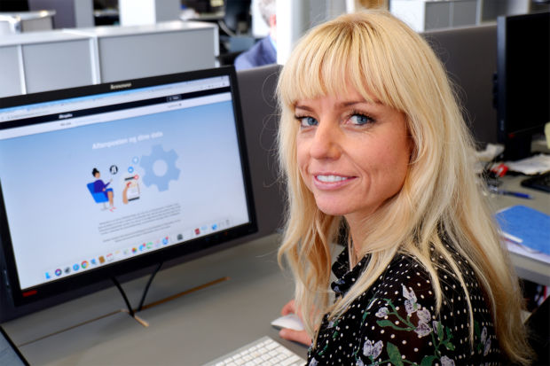 En kvinne med lyst hår sitter foran en data, vend mot kamera. På skjermen vises Aftenpostens personverninstillinger.