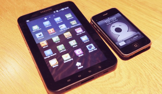 en Samsung Galaxy Tab og en iPhone. iPhone'n har et skjermsparerbilde med et skrikende barn