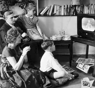 sorthvitt-foto av en 1950-talls familie samlet foran TV