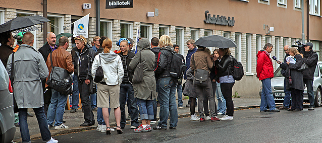 En stor ansamling svensker står utenfor et valglokale og diskuterer. I utkanten av bildet blir en mann intervjuet av et TV-team