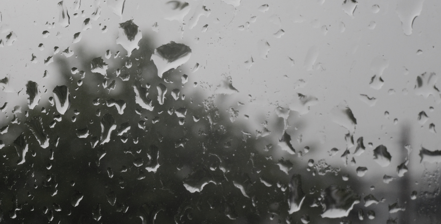 Foto av regndråper på et vindu. Gråvær på utsiden.