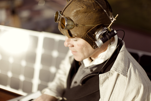 Thomas Dolby i antikk lærhjelm med sveisebriller på hodet og lykt på siden av hjelmen. I bakgrunnen solpaneler.