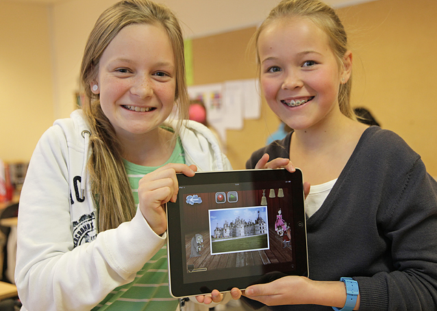 To smilende jenter holder opp en iPad med en Puppet Pals-film