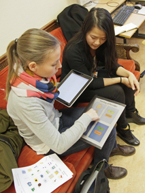 To kvinnelige studenter sitter med en iPad og en bunke skisser