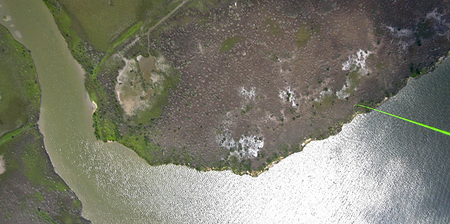 Landskap med sjø og land sett fra luften. I billedkanten sees ballonglinen som går ned til bakken
