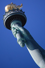 fotoutsnitt av Frihetsgudinnen - hånden som holder en fakkel - mot blå himmel