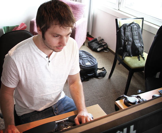 Foto av en mannlig journalist i hvit T-skjorte sittende ved en PC i et hotellrom.