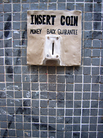 en keramikk-skulptur av et myntinnkast med åpen underside. Tekst:"Insert Coin - Money Back Guarantee"
