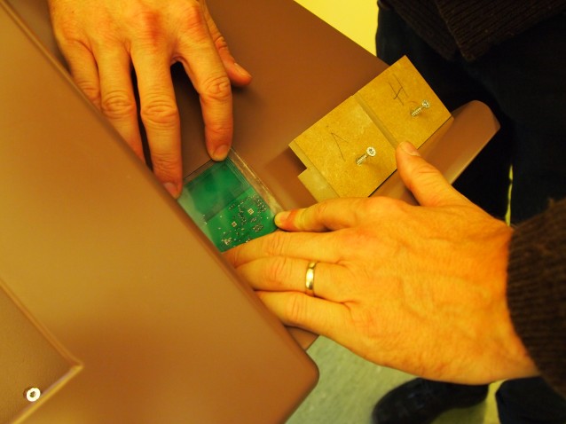 To hender monterer et printkort på Aktive Hyller-stasjonen