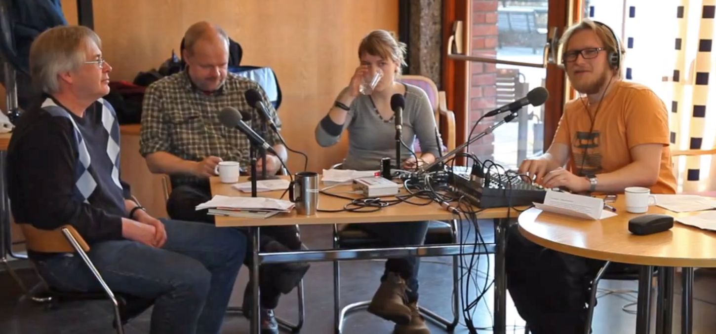 Fire personer rundt et bord med mikrofoner, kabler, et miksebord - radiosending
