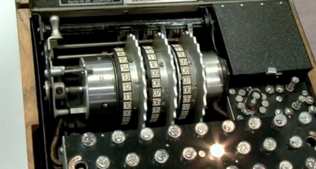 Skjermskudd av Enigma-maskin; et skrivemaskinliknende apparat med store roterende tall-skiver