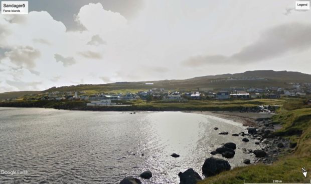 Bilde av en bukt i Tórshavn, hvor vi ser sjøen og et akvarie og annen bebyggelse på andre siden av stranden.