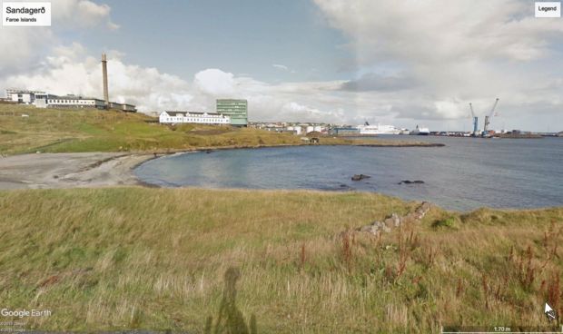 Bilde fra Google Earth som viser en strand og innsjø, med blant annet kranene på Tórshavns havn synlige til høyre i bildet.