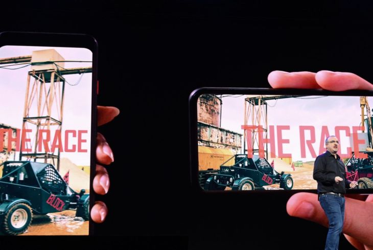 En mann står på en scene foran et bilde av to mobiler. Den ene holdes vertikalt og den andre horisoltalt.