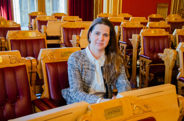 En kvinne sitter på en stol i Stortingssalen merket "Akershus".