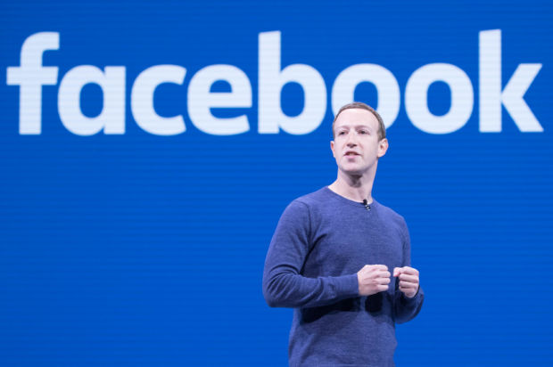 Facebooks grunnlegger Mark Zuckerberg står foran en Facebook-logo
