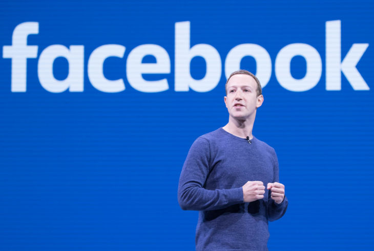 Facebooks grunnlegger Mark Zuckerberg står foran en Facebook-logo