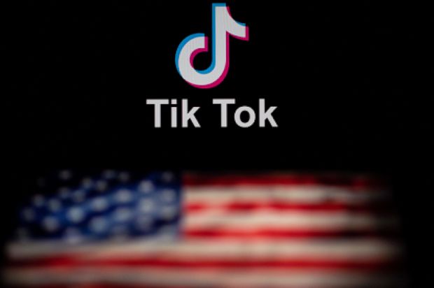 En TikTok-logo svever over et amerikansk flagg på en sort bakgrunn.