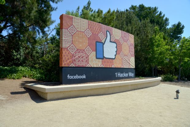Et stort skilt foran noen trær, med en stor Facebook-tommel på.