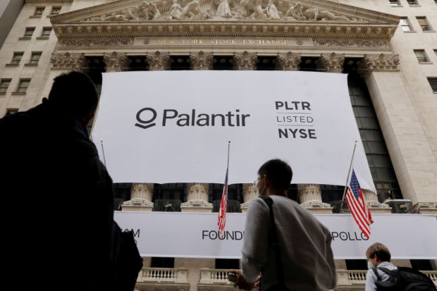 Mennesker går forbi et enormt banner utenfor en børs i New York, hvor det står Palantir.